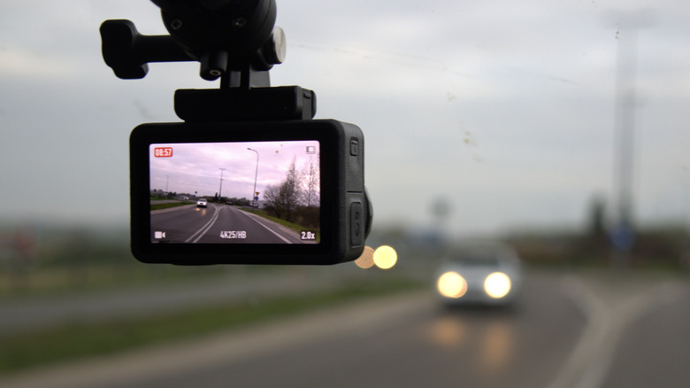 A dashcam affixed to a vehicles windshield recording video of an oncoming car