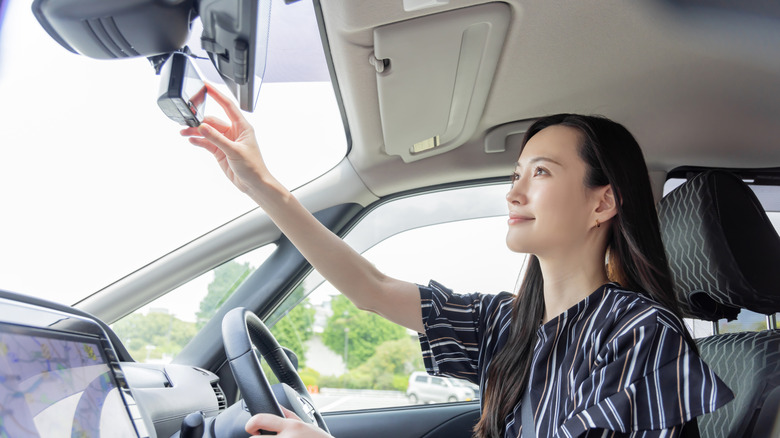 A woman adjusting a newly installed dashcam in her car