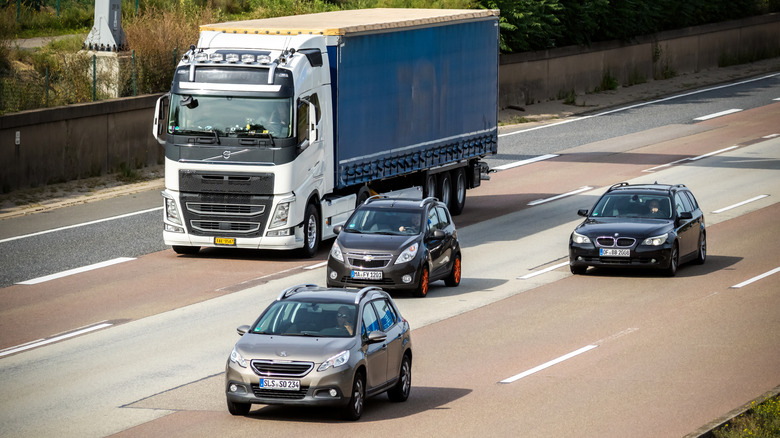 Traffic flowing on the autobahn, with a big rig in the background plus a handful of passenger vehicles in the foreground.