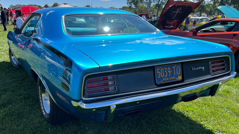 A blue 1970 383 Plymouth Cuda parked on grass at a car show