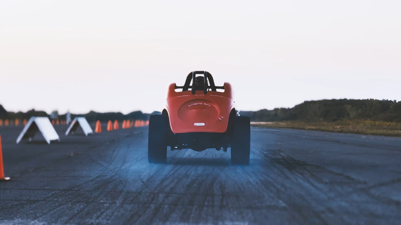 A vintage red dragster accelerates from the starting line