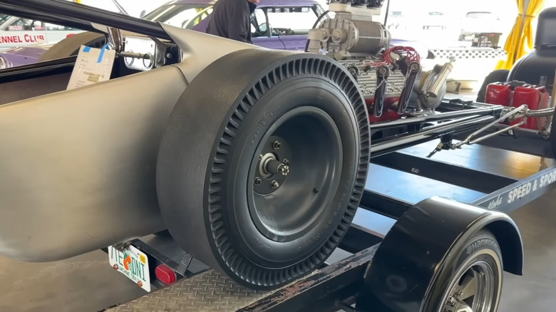 A closeup of the piecrust recapped drag slick tires on a vintage dragster with a supercharged flathead Ford V8