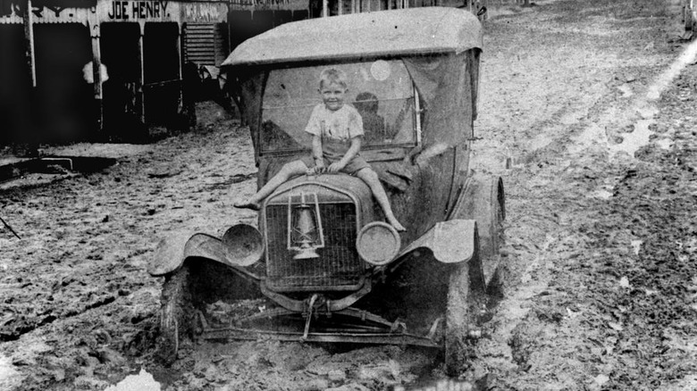 A child sits on the hood of a Ford Model T in the mud after a flood in March 1925 in Queensland, Australia.
