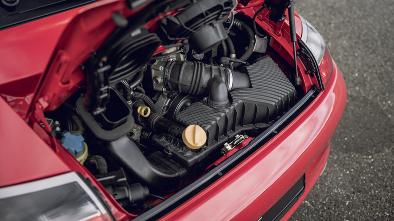 The open rear engine compartment of a red 996 generation Porsche 911 Targa.