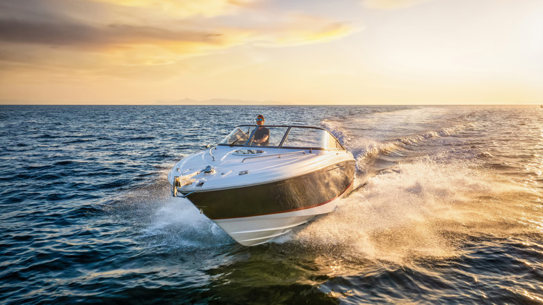 Stock image of a man on a motorboat during sunset.