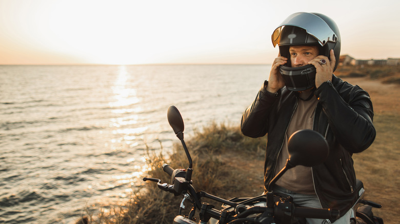 Safety riding. Man arrived on the coast by motorcycle to rest at sunset. Beautiful coastline in remote location. Travel alone.