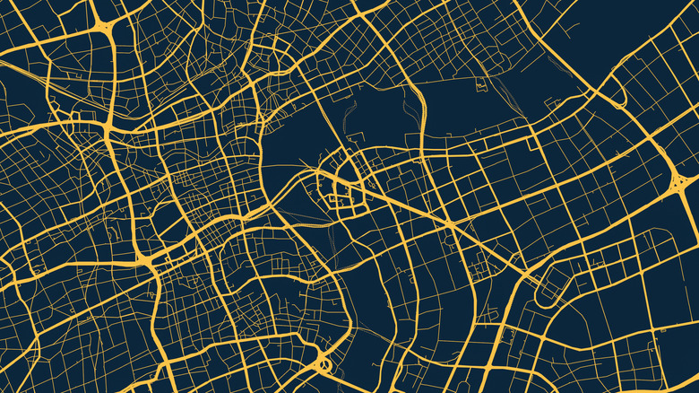 An abstract city map of an unknown area, black background with yellow street and highway lines.