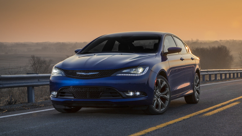 A Chrysler 200 drives on a highway as the sun goes down.