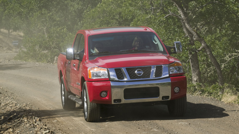 A red 2009 Nissan Titan on an unpaved road.