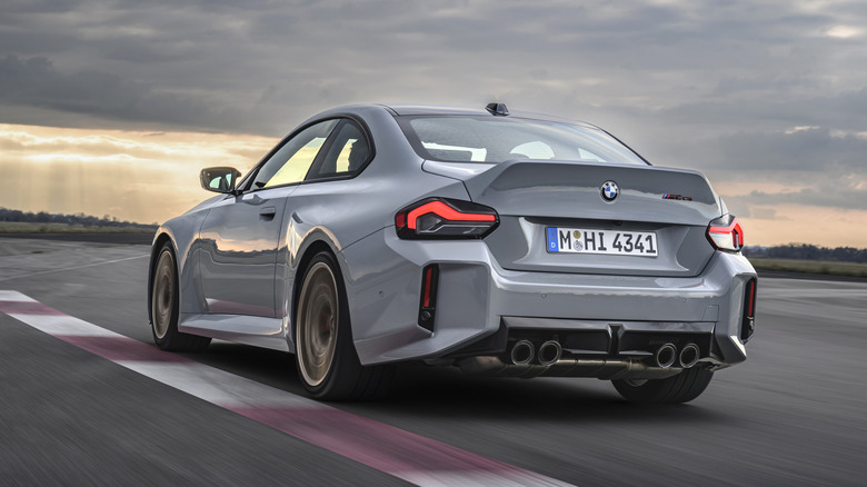 A rear three-quarter view of a gray BMW M2 CS being driven on a track.