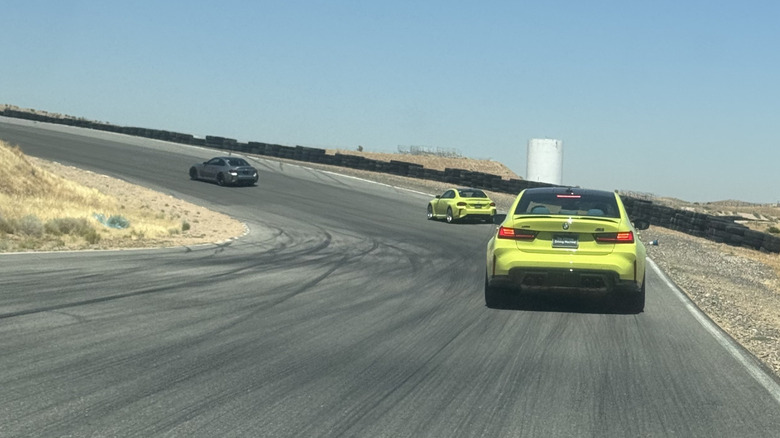 A photo of the rear of a highlighter yellow M3 following a highlighter yellow M2 following a gray M2 around a corner