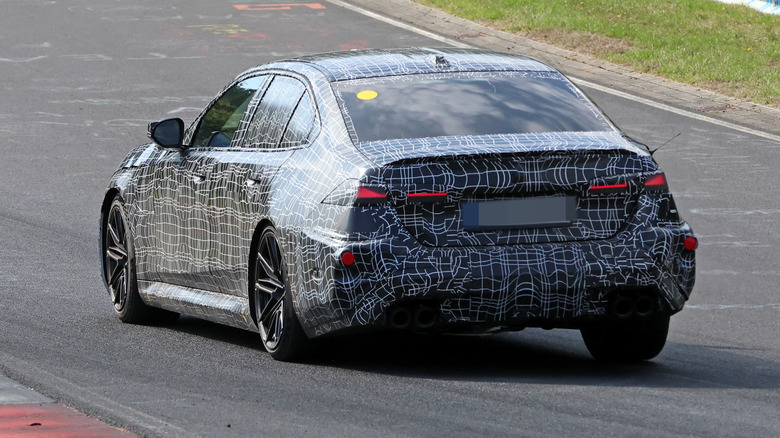 Rear 3/4 view of a camouflaged BMW M5 prototype