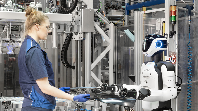 An Aeon robots holding a glass pane with a human worker at BMW's Leipzig assembly plant
