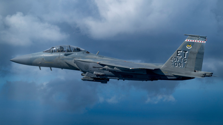 An F-15EX Eagle II in flight against a partly cloudy sky