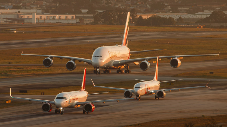Several Boeing and Airbus aircraft lined up on a tarmac.