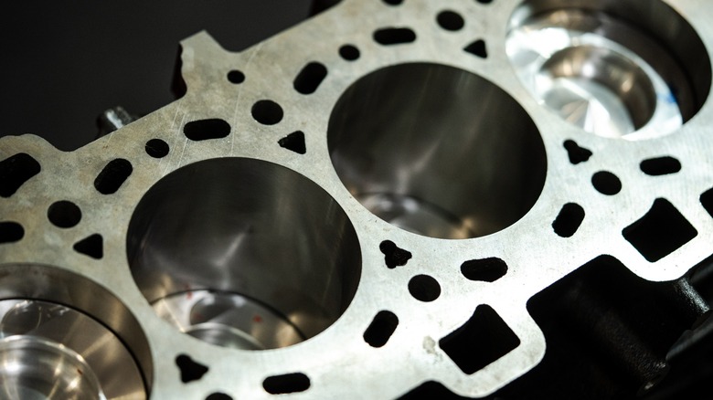 A partially disassembled engine block showing the piston tops inside the cylinders.