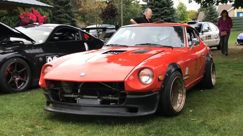 Red Datsun 280Z at car show featuring Mercedes M120 V12