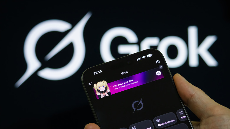 Blurry Grok logo in the background, a hand holding a cell phone in the foreground open to Grok