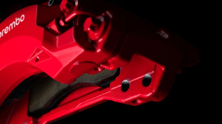 A close-up shot looking between the pads of the red Boldika caliper in front of a black background