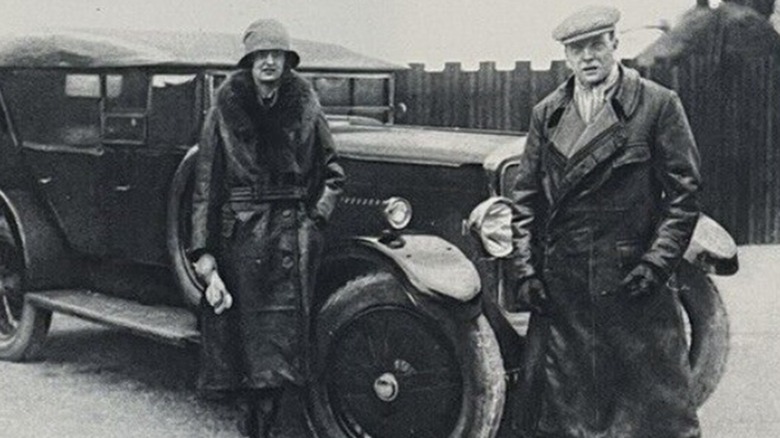 The earl and duchess of Cottenham standing next to one of their luxury automobiles