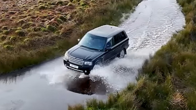 A 2009 Land Rover Range Rover driving in a river in the wilderness