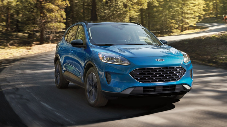 Blue 2022 Ford Escape drives along a forested road.
