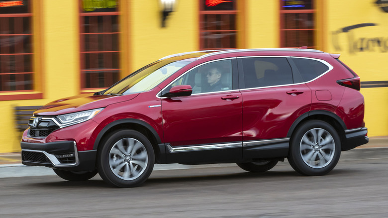 2020 Honda CR-V drives along a road in front of a colorful restaurant.
