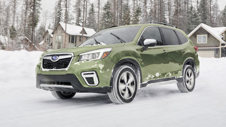 2020 Subaru Forester driving on snow covered road with homes behind it.