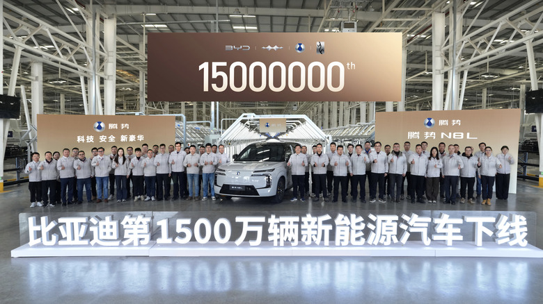 View of BYD factory workers flanking the company's 15 millionth vehicle, with a large sign reading "15000000" overhead