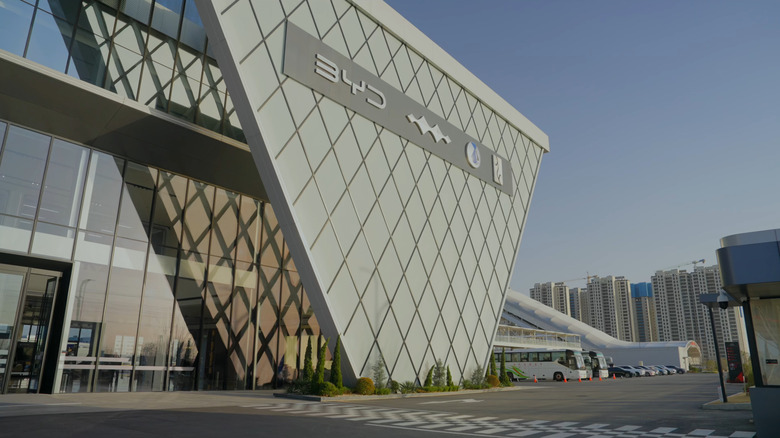 Entrance to all-terrain circuit at BYD's massive Zhengzhou facility showing modern facade with buses and buildings in background