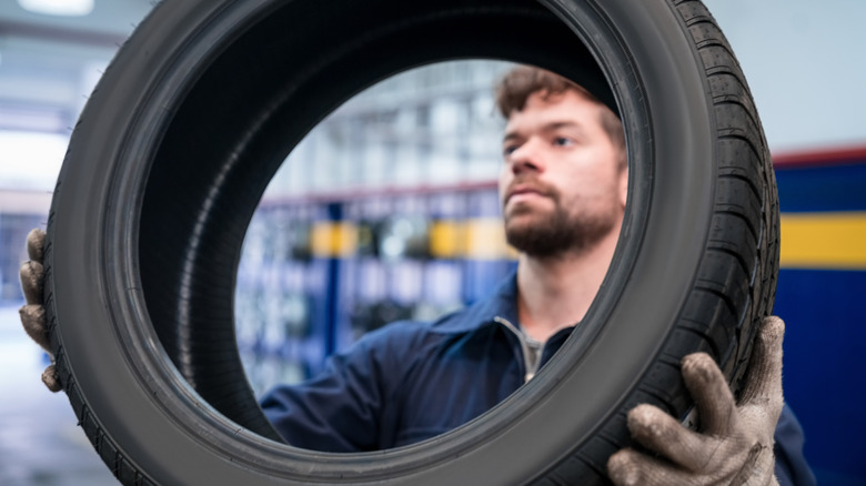 A tire tech holding up a tire inside a repair shop