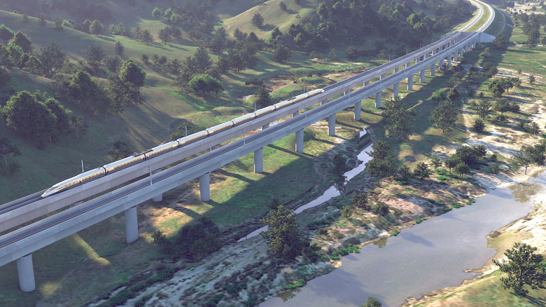 overhead rendering of the CA bullet train winding through a natural California landscape on a raised bridge
