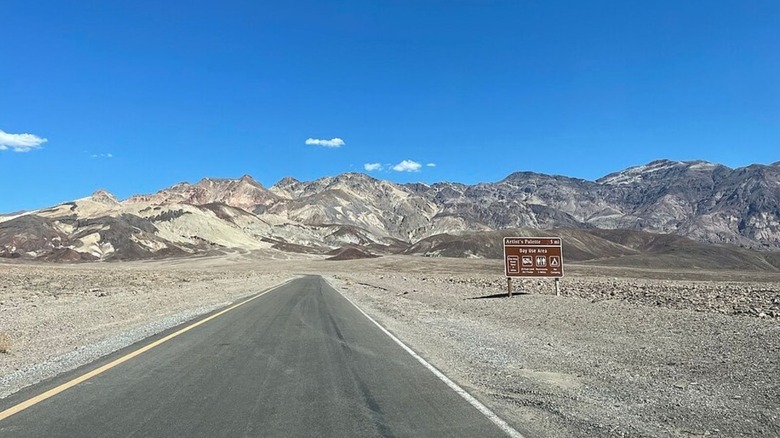 A straight section of Badwater Road in California, with mountains and a blue sky in the distance