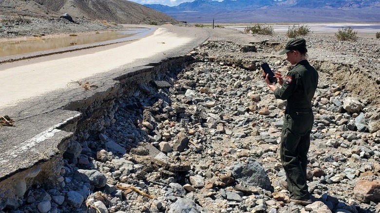A worker surveying a washed-out section of Badwater Road after severe rain and flooding