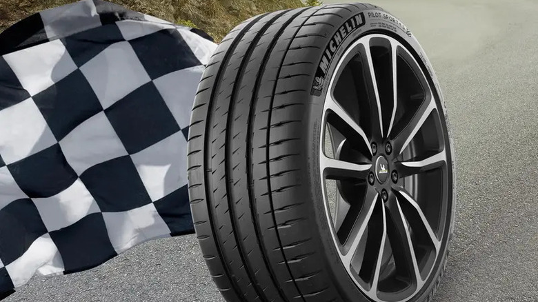 3/4 view of a Michelin Pilot Sport 4 S tire on a rim with a checkered flag to the left
