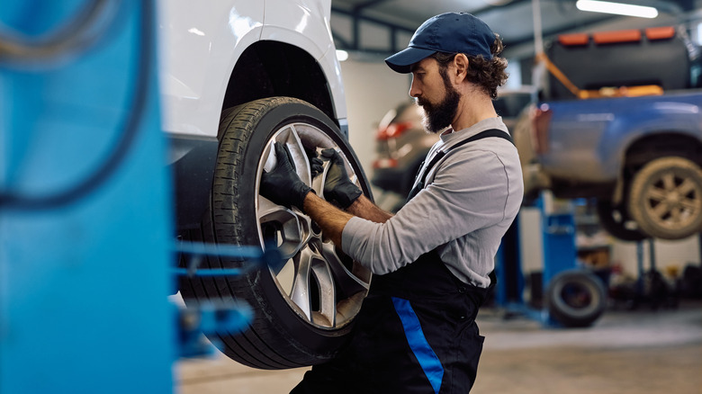 A tire technician removing a wheel from a car on a lift