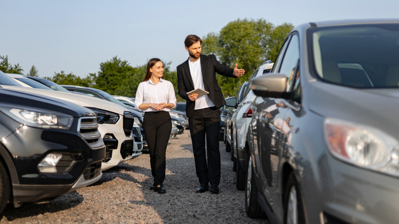 Two group stepping among cars astatine a dealership.