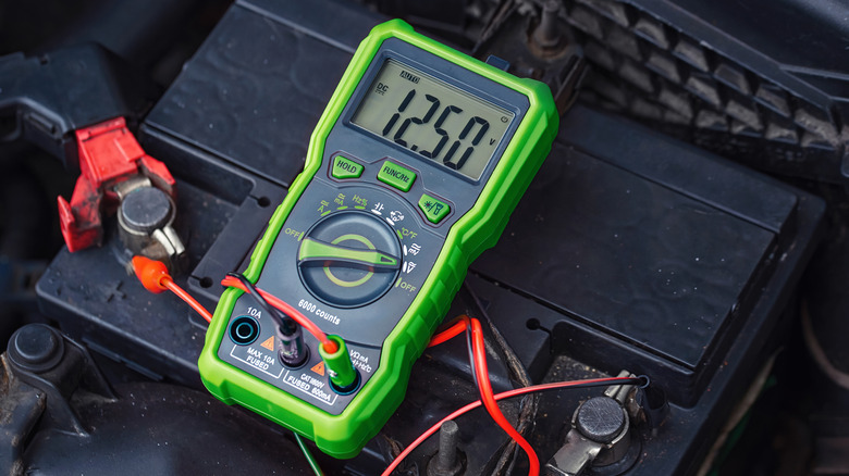 A voltmeter positioned above a car battery
