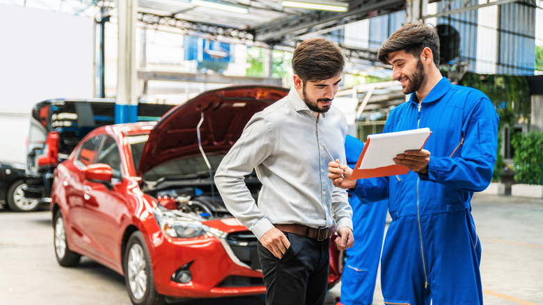 A mechanic showing nan car checklist to nan customer