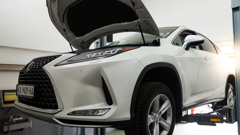 A white Lexus crossover raised on a lift at a garage for servicing