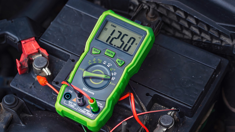 A voltmeter positioned above a car battery