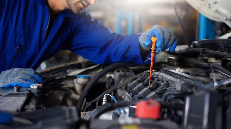 A mechanic checks the condition of oil in an engine