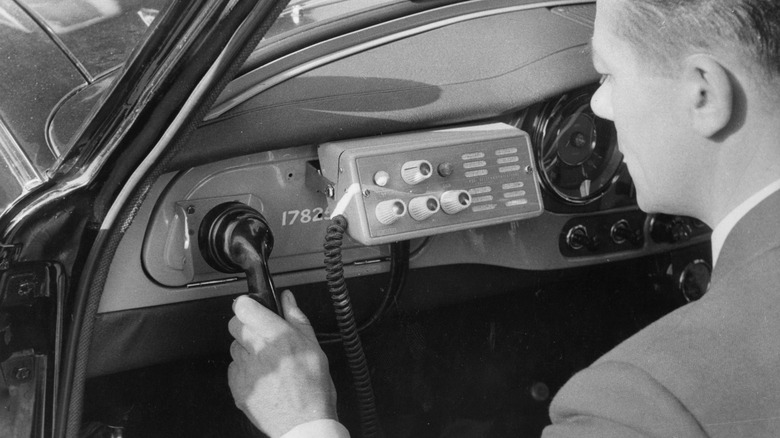 Driver using one of the earliest car phones ever made.