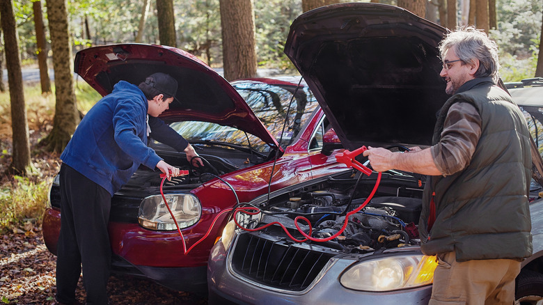 An older and younger man jump-starting a car