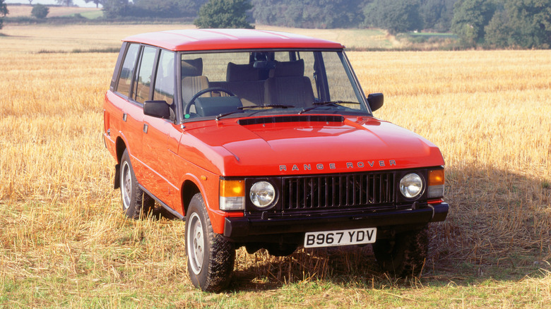 A stock Range Rover Classic in red, sitting in a field