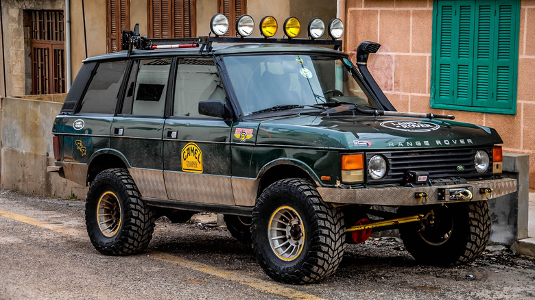A dark green modified off-road Range Rover Classic in front of a building