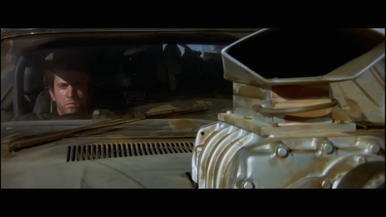 Max Rockatansky sitting in the driver's seat of his XB Falcon Pursuit Special, with a supercharger visible in the foreground