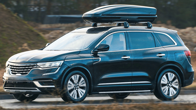 An SUV with a hard shell cargo carrier on a roof rack