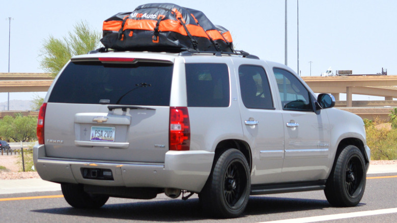 An SUV driving with a cargo bag fixed to the roof
