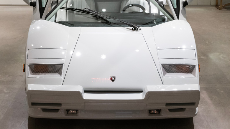 A white Lamborghini Countach sits on a concrete floor